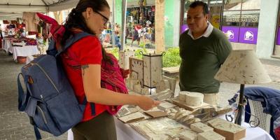 Compradora observa el producto de uno de los empresarios.