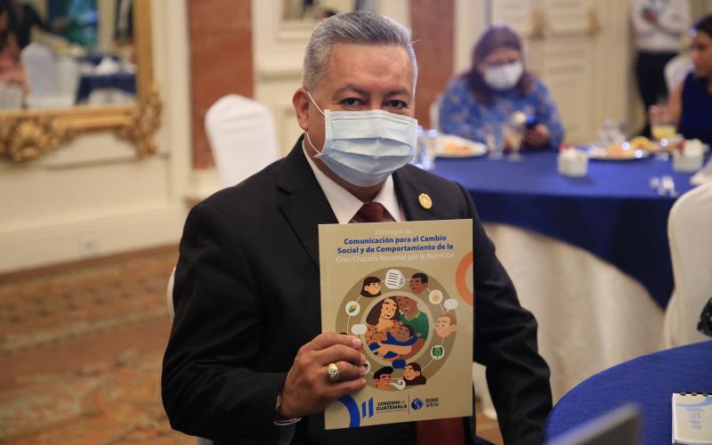 Ministro de Desarrollo con documento de estrategia de comunicación para cambio de comportamiento