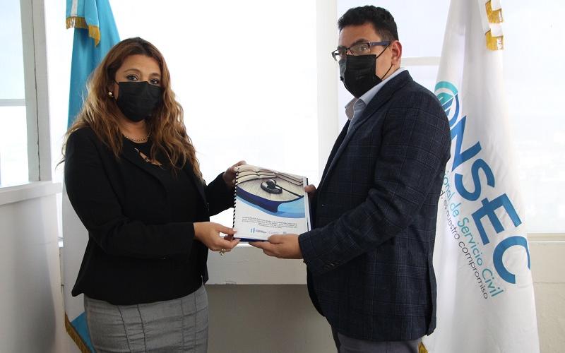 La Directora de la Onsec entrega el acuerdo firmado al Director de Puestos y Remuneraciones