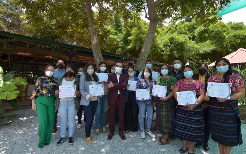 Grupo de Personas entre hombre y mujeres, tienen como fondo un árbol, reciben reconocimientos por capacitación