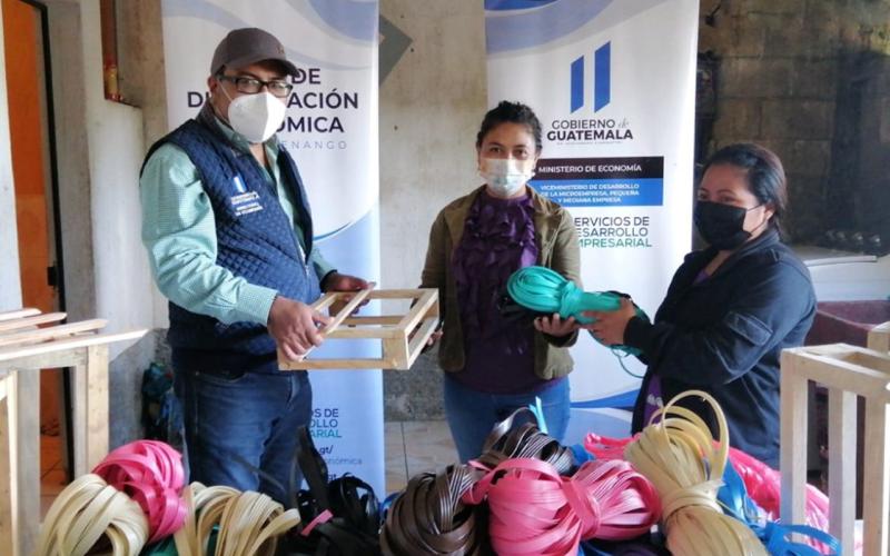 Tres personas en la foto reciben inducción sobre elaboración de cestas artesanales.