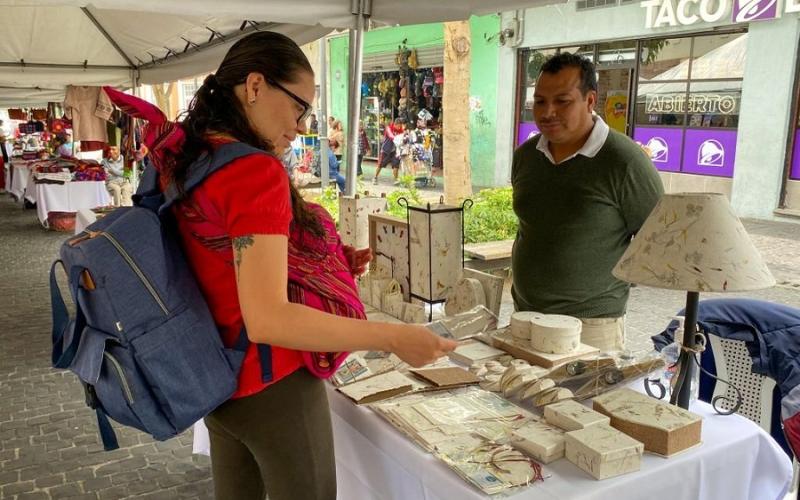 Compradora observa el producto de uno de los empresarios.