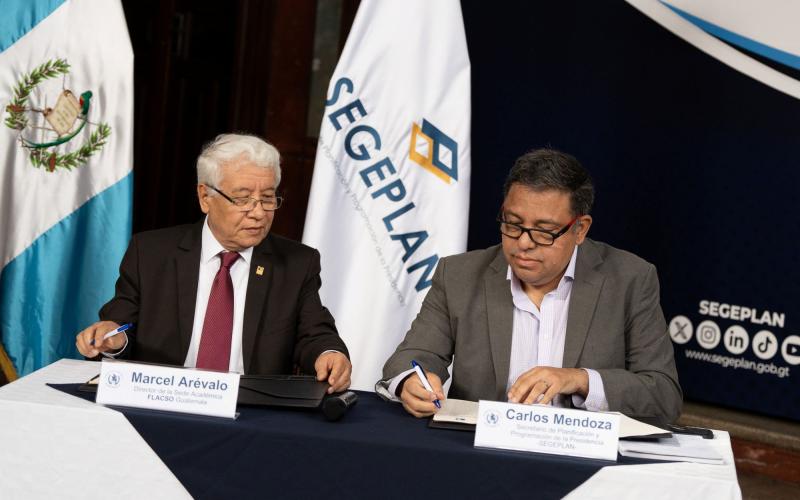 El titular de SEGEPLAN, Carlos Mendoza y el director de FLACSO, Marcel Arévalo, firman el convenio.