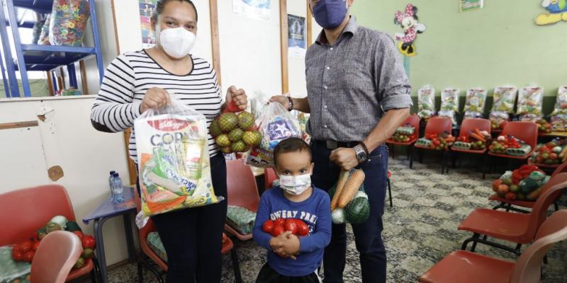 En el CADI de Palencia, uno de los niños beneficiarios recibe junto a su mamá la bolsa de aliementos