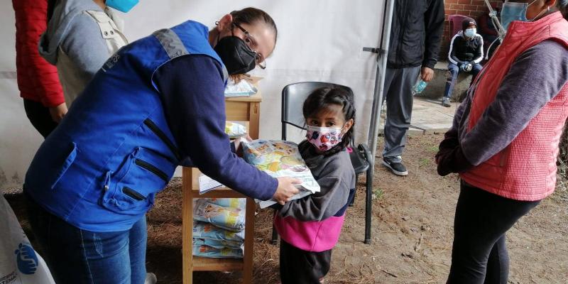 Personal Mides entregando alimento a niña