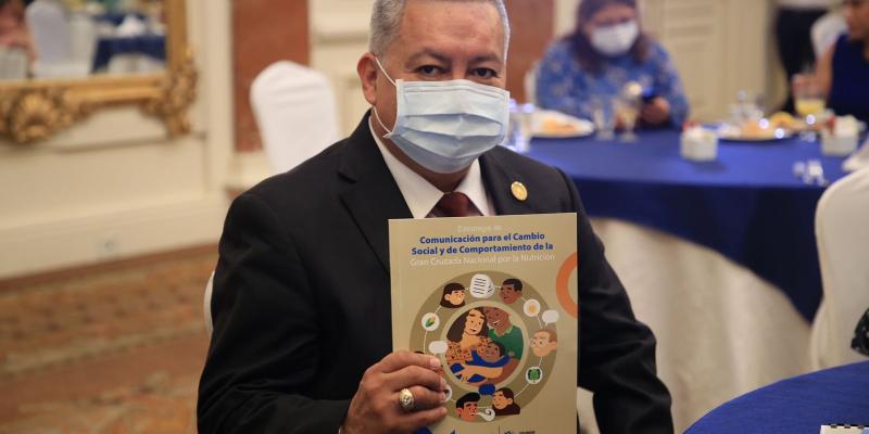 Ministro de Desarrollo con documento de estrategia de comunicación para cambio de comportamiento