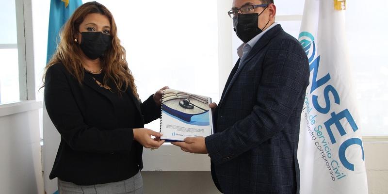 La Directora de la Onsec entrega el acuerdo firmado al Director de Puestos y Remuneraciones