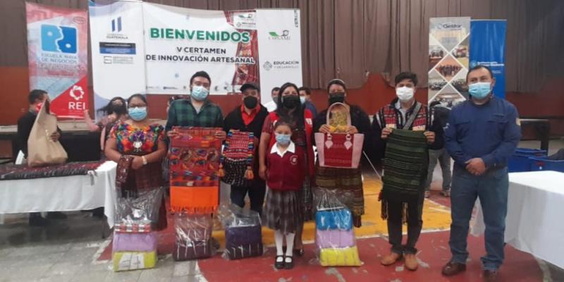 Personas de pie posan para foto donde muestran sus trabajos elaborados.