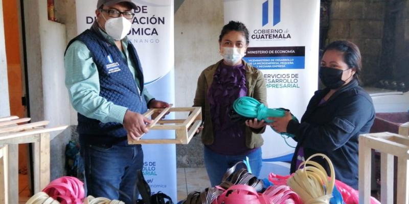 Tres personas en la foto reciben inducción sobre elaboración de cestas artesanales.