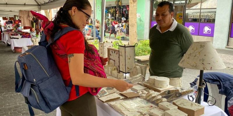 Compradora observa el producto de uno de los empresarios.