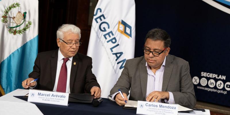 El titular de SEGEPLAN, Carlos Mendoza y el director de FLACSO, Marcel Arévalo, firman el convenio.